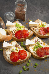 sandwich of spicy salami and cheese on a black wooden table.