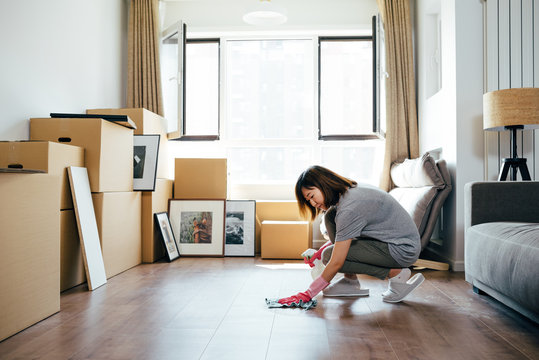 Young woman polishing wooden floor at new home