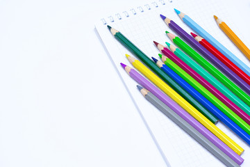 Color pencils for drawing with a notebook on a white background. Background.