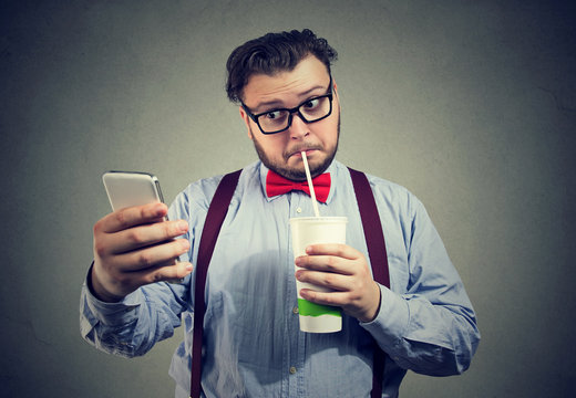 Addicted to sugar man drinking soda and using phone