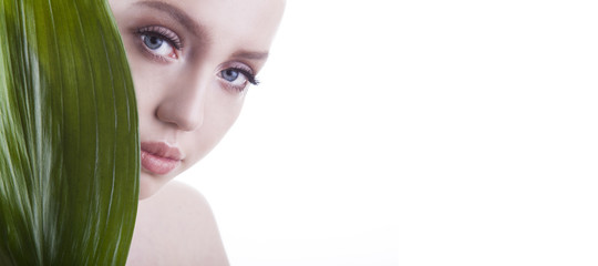 Naklejka premium Beauty shoot. European, young, blue-eyed woman posing with fresh, green leaf.