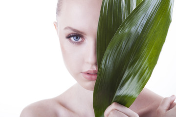 Beauty shoot. European, young, blue-eyed woman posing with fresh, green leaf.