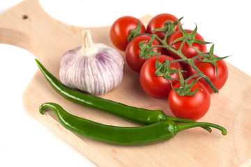 tomatoes, garlic and green peppers on the wooden cutting board, white background