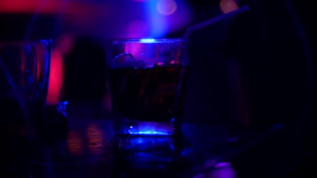 Closeup of alcohol cocktail in glass on bar counter, in nightclub. background blur, 4k