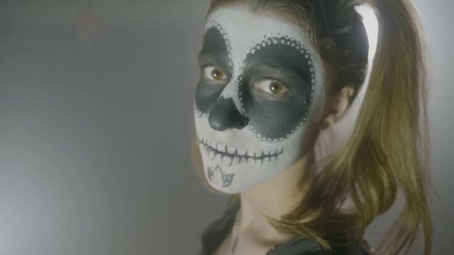 Malefic doll portrait of a halloween possessed woman with makeup on face and big eyes looking at the screen