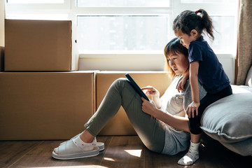 Adorable girl and her mother using digital tablet and moving