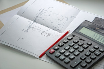 The plan is a project of a residential attic house. Red pencil and calculator on a white background