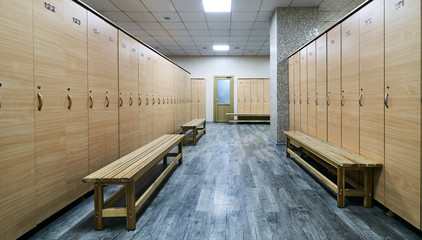 Interior of a locker room. Clean empty dressing room with big lockers and wooden bench