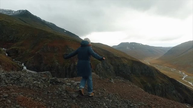 Happy hiker with her arms outstretched, achievement in mountains