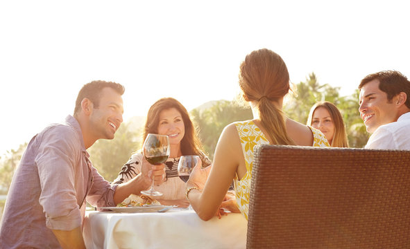 Friends Having Dinner And Wine In A Tropical Location Outdoors