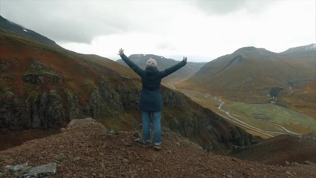 Happy hiker with her arms outstretched, achievement in mountains