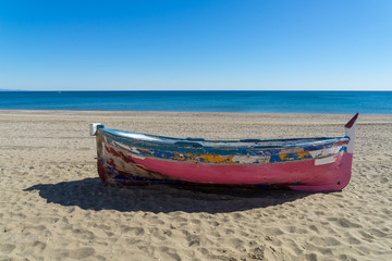 Fototapeta na wymiar bunt gestrichenes und verwittertes Ruderboot am Strand