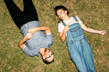 adventurous couple laying in grass after getting wet fully clothed in pool water