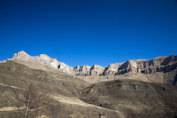 Fototapeta na wymiar Горный пейзаж, Красивый вид на высокие скалы, живописное горное ущелье, вершины на фоне синего неба. Дикая природа Северного Кавказа, путешествие и туризм
