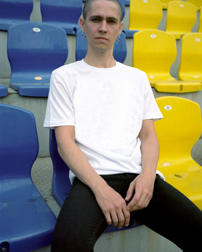 Young man sitting on colourful stadium seats