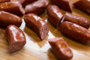 Spicy sausage chorizo cut in pieces on a hard wood cutting board - close up