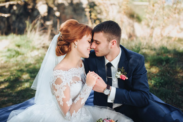 Gentle kiss of the bride and groom. Loving newlyweds at a picnic. Wedding walk. The red-haired bride.