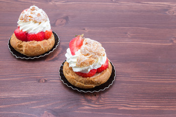Chou aux fraises - Tart with strawberries and whipped cream. Side view on a ipe table