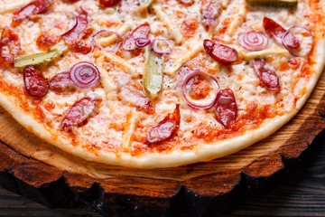 Delicious pizza texture with salami, onions and gherkins and appetizing crust close up. Food background