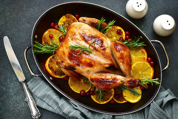 Roasted chicken with oranges, rosemary and cranberries in a skillet pan.Top view .