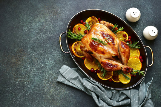 Roasted chicken with oranges, rosemary and cranberries in a skillet pan.Top view with copy space.