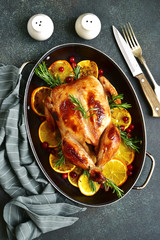Roasted chicken with oranges, rosemary and cranberries in a skillet pan.Top view .