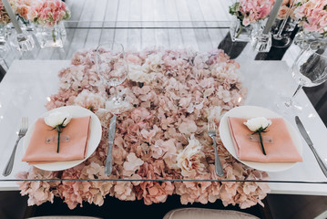 Banquet. Wedding. The glass table is decorated with a lot of beautiful pale pink flowers, with...