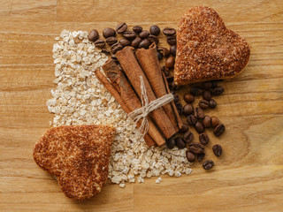 oatmeal and coffee beans and cinnamon sticks and cinnamon cookie hears on wooden table