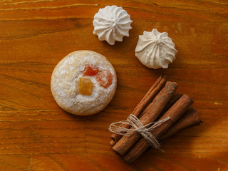cookie and meringues and cinnamon sticks on wooden table