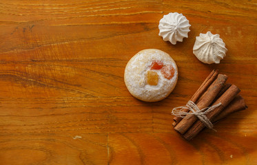 cookie and meringues and cinnamon sticks on wooden table