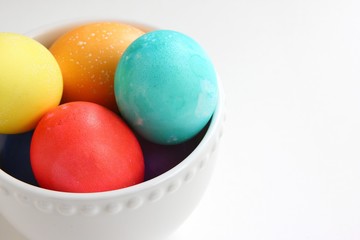 Colored Easter eggs in a white bowl, isolated on a white background.