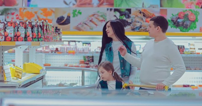 Young couple and children in frozen section. Woman taking prepack from the fridge