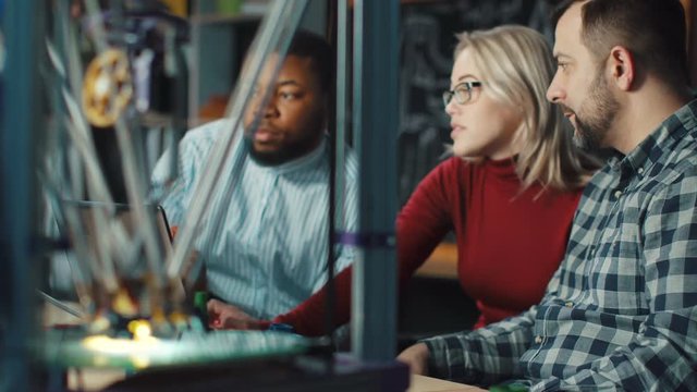 Group of multiethnic scientists watching process of 3d printing in work. Static 4K shot on Red cinema camera.