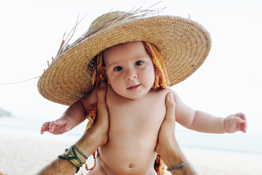 Baby In A Big Straw Hat On A Beach At Holiday Vacation