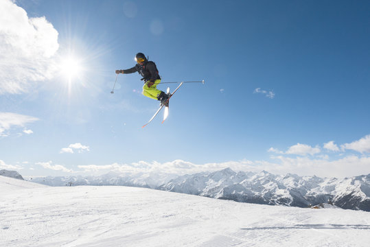 Male skier jumping in midair while freeriding off piste
