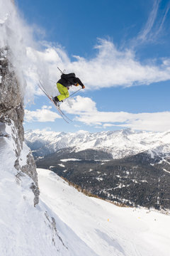 Extreme freerider skiing off piste and jumping from high cliff