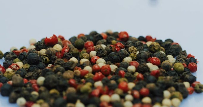 Macro of the pepper peas faling down on the white surface. Close up