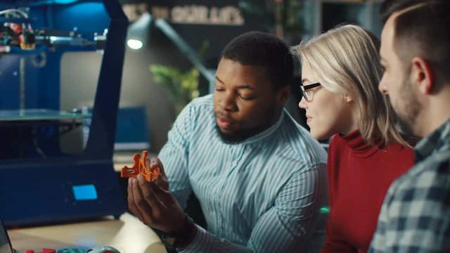Group of multiracial scientists discussing process of contemporary 3d printing and future possibilities. Static 4K shot on Red cinema camera.