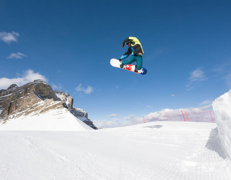 Man with snowboard jumping in midair on a bright winter day