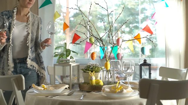 Young woman is setting easter festive table with bunny and eggs decoration. Slow Motion