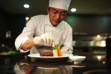 Professional cook garnishing dish