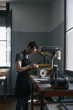 Artisan glasses maker is working with machinery in his atelier