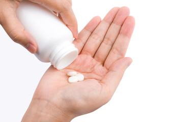 Adult woman hand pouring tablets pills out of white plastic bottle in to her hand isolated on white background. Health care in adult people