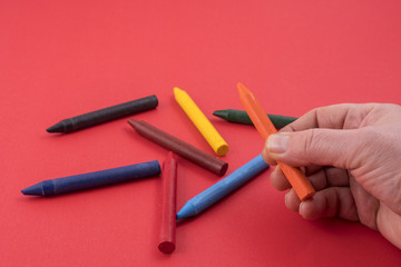 some colored wax crayons on a red surface