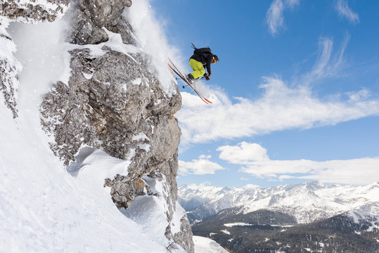 Male skier jumping in midair from snow-capped cliff