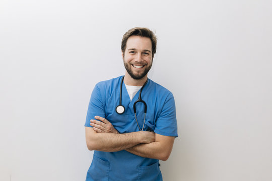 Portrait of smiling doctor standing against white background