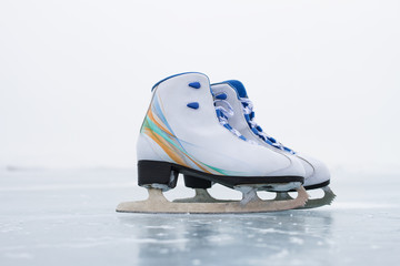 A pair of new leather skates in the snow on the ice of the sacred Lake Baikal in winter on a cloudy windy snowy day.