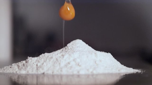 Close up of egg falling into flour