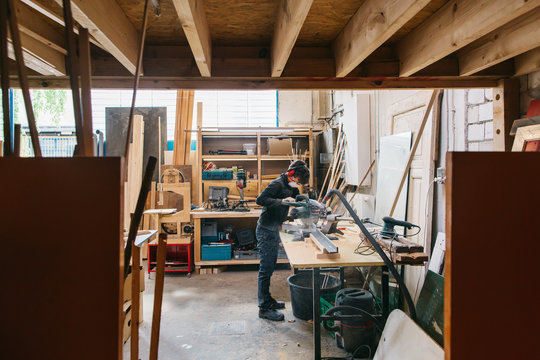 Female Carpenter Cutting Wood in Bright Workshop Space