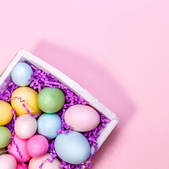 Fototapeta na wymiar Multicolor eggs in a white tray. Creative Easter concept. Modern solid pink background.